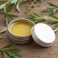Mugwort beeswax salve in a round silver tin with silvery green mugwort leaf sprigs