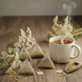 Yarrow herbal tea bags beside a steaming mug of golden tea with dried yarrow flowers